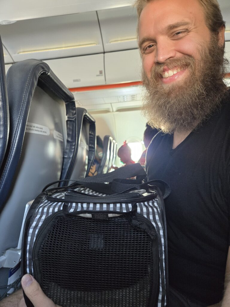 Teddy holding Susie's cat carrier on the plane