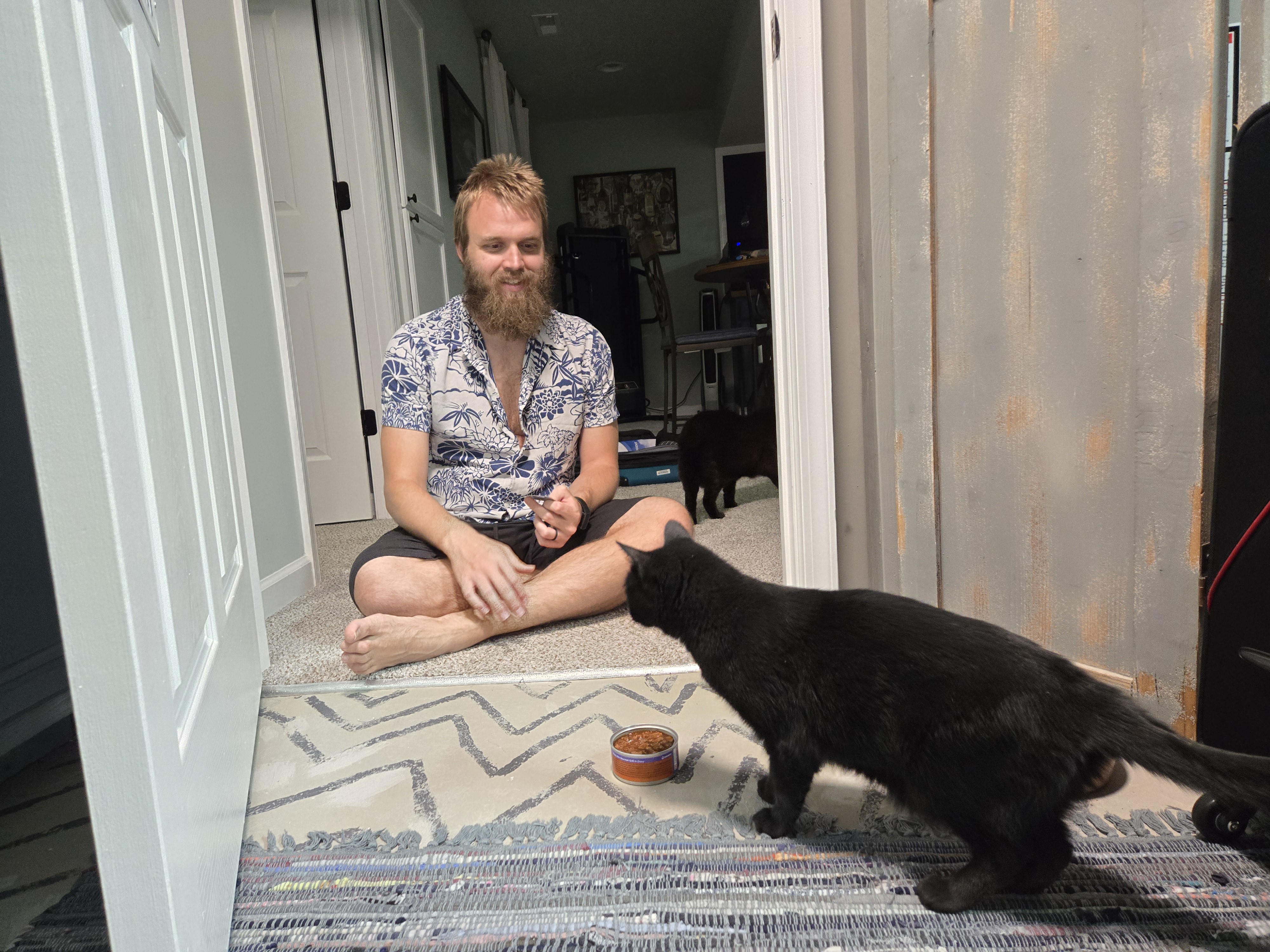 Teddy sitting cross-legged in front of Xena and a can of food