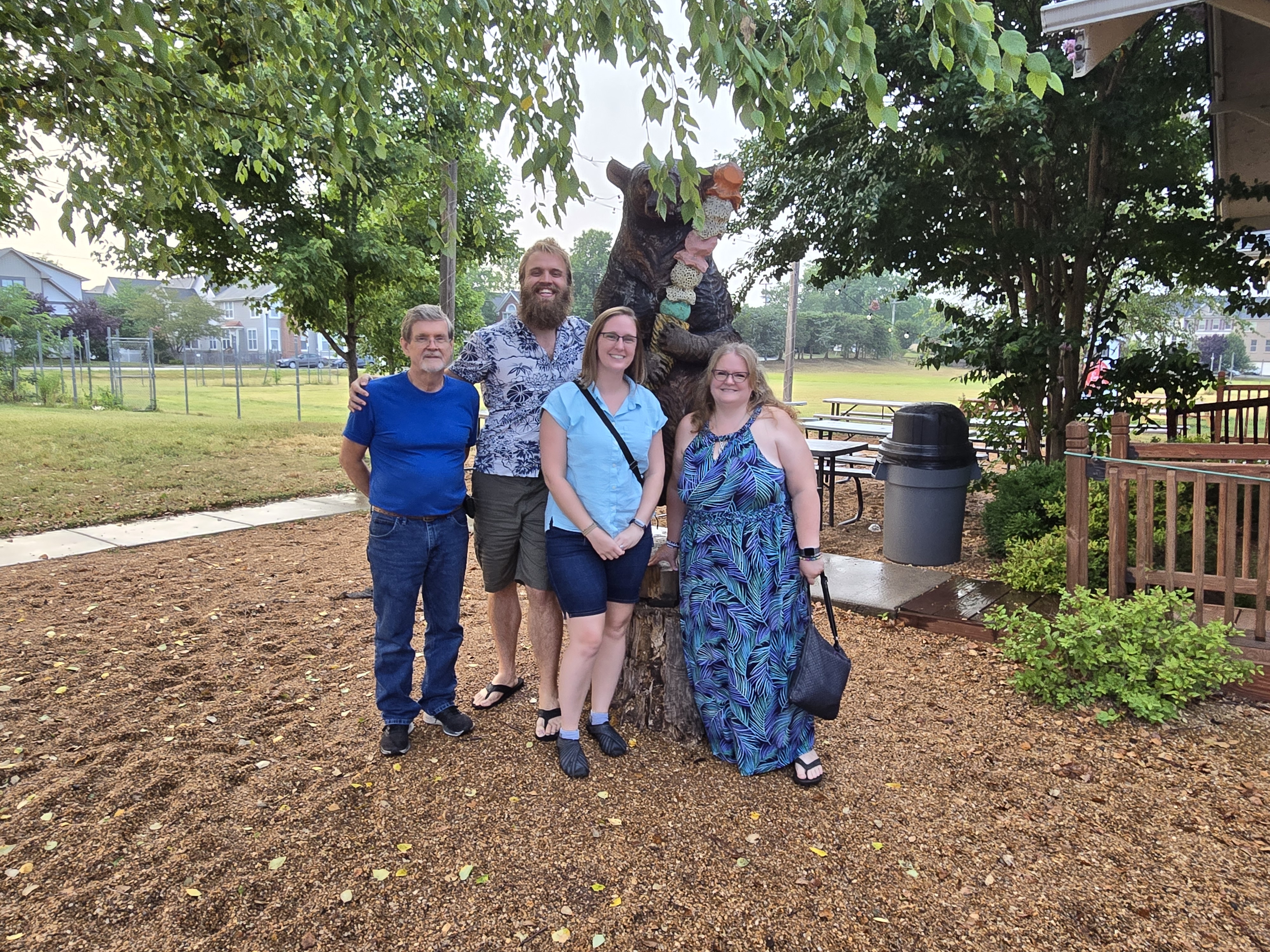 Teddy, Cassie, Chris, and Pam standing in front of a carved bear.