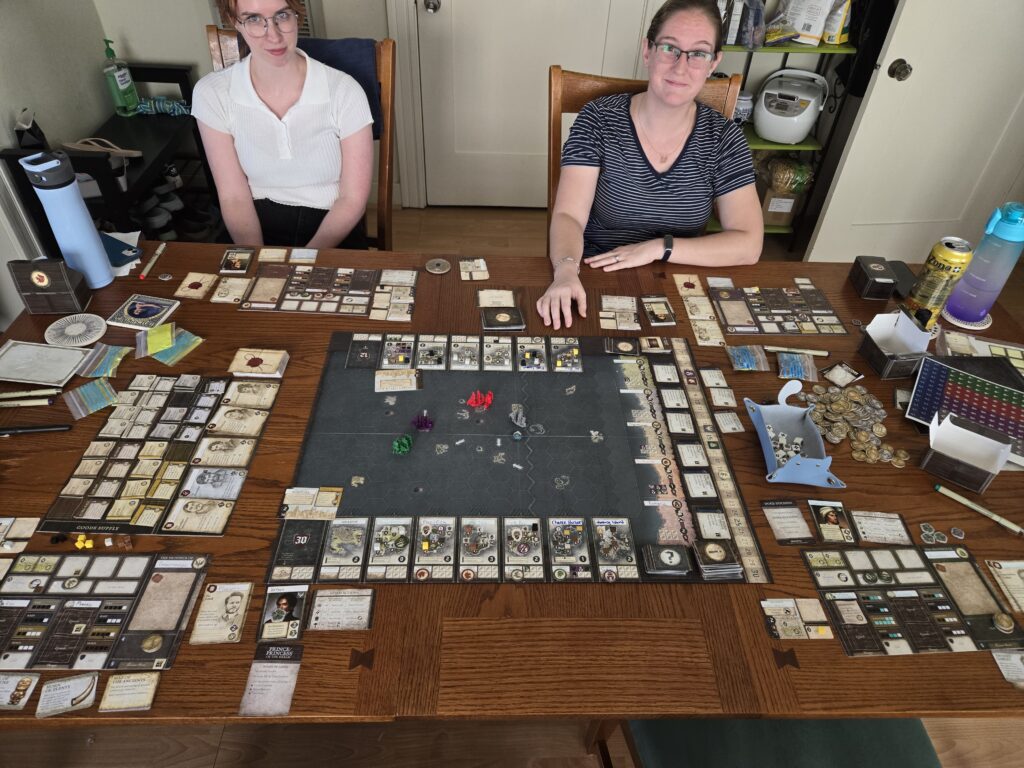 Cassie and Lizzy sitting in front of a set-up Seafall board.